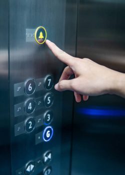 Male forefinger pressing on emergency stop and alarm button in elevator (lift). Mechanical engineering concept